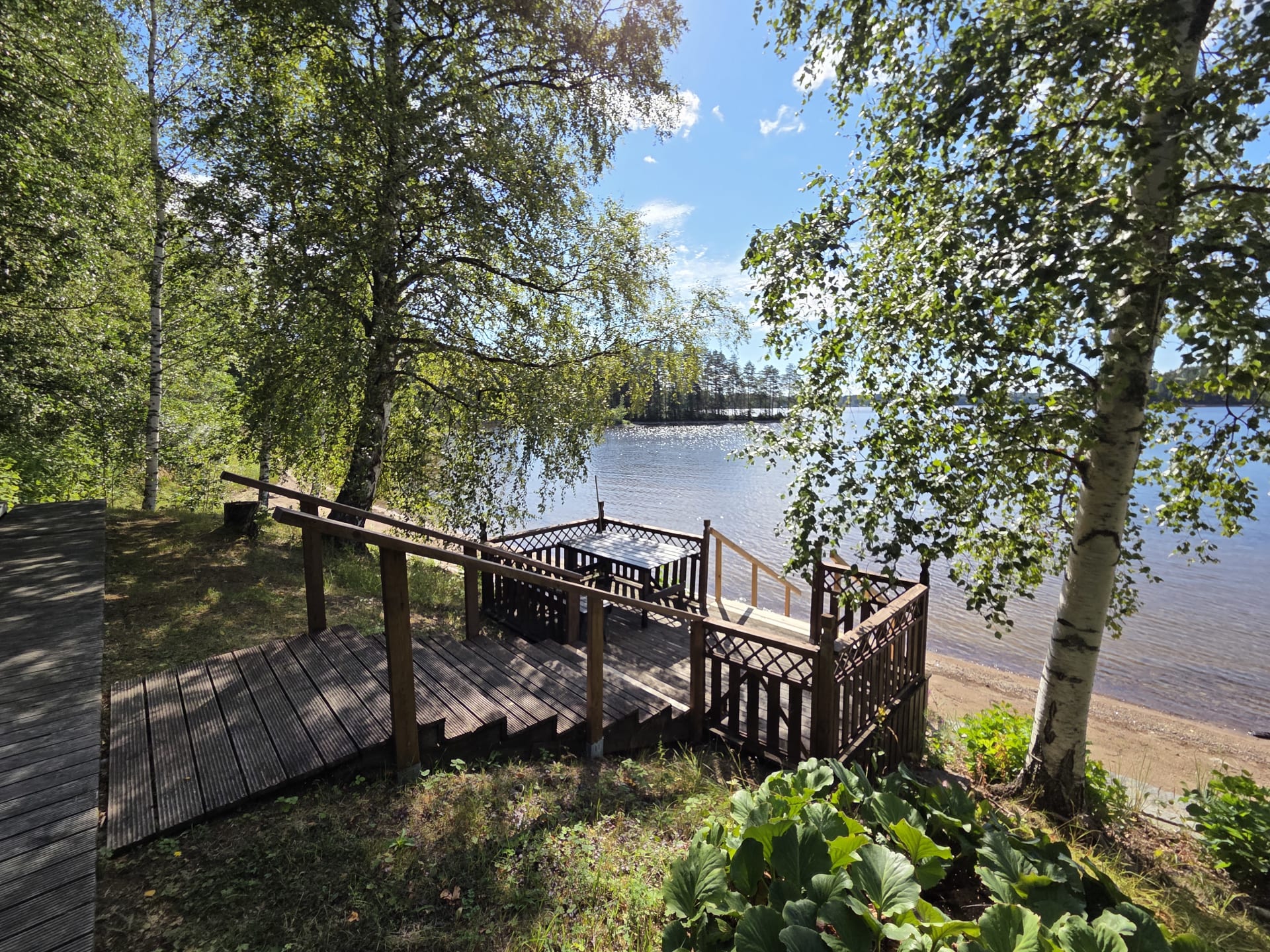 Close-up of a wooden brown terrace and stairs on the shore of a blue lake