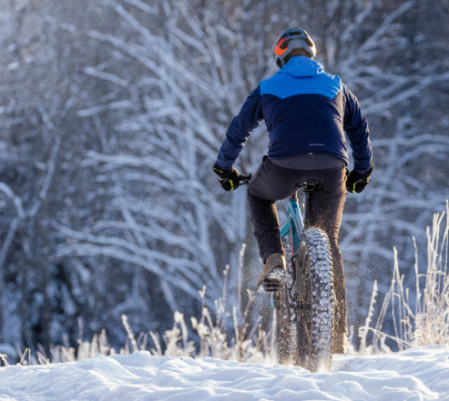 Pyöräilijä talvisessa metsässä